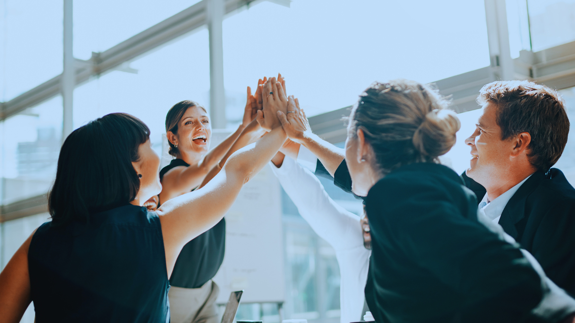 Energiek HR-team dat elkaar high-fived, omdat het impact maakt in een kantooromgeving.